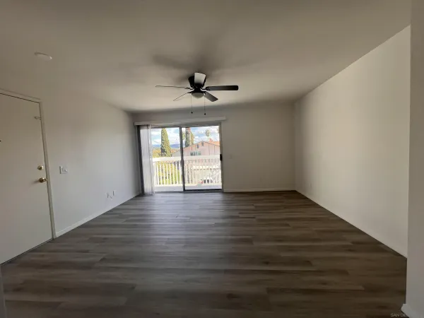 a view of an empty room with a window and wooden floor