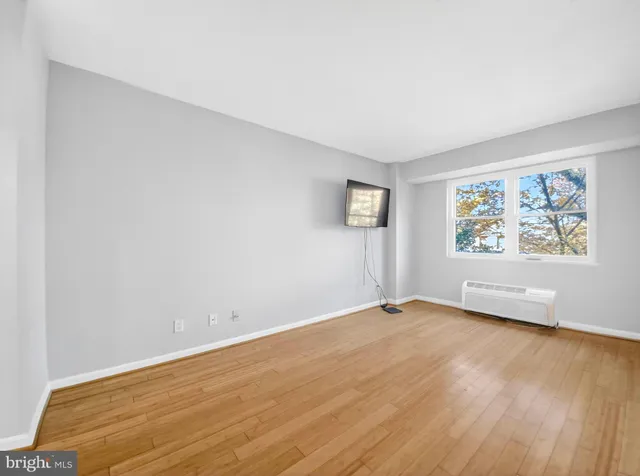 an empty room with wooden floor and window