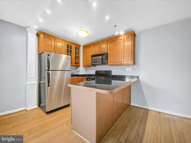 a kitchen with stainless steel appliances granite countertop a refrigerator a stove a sink and a microwave