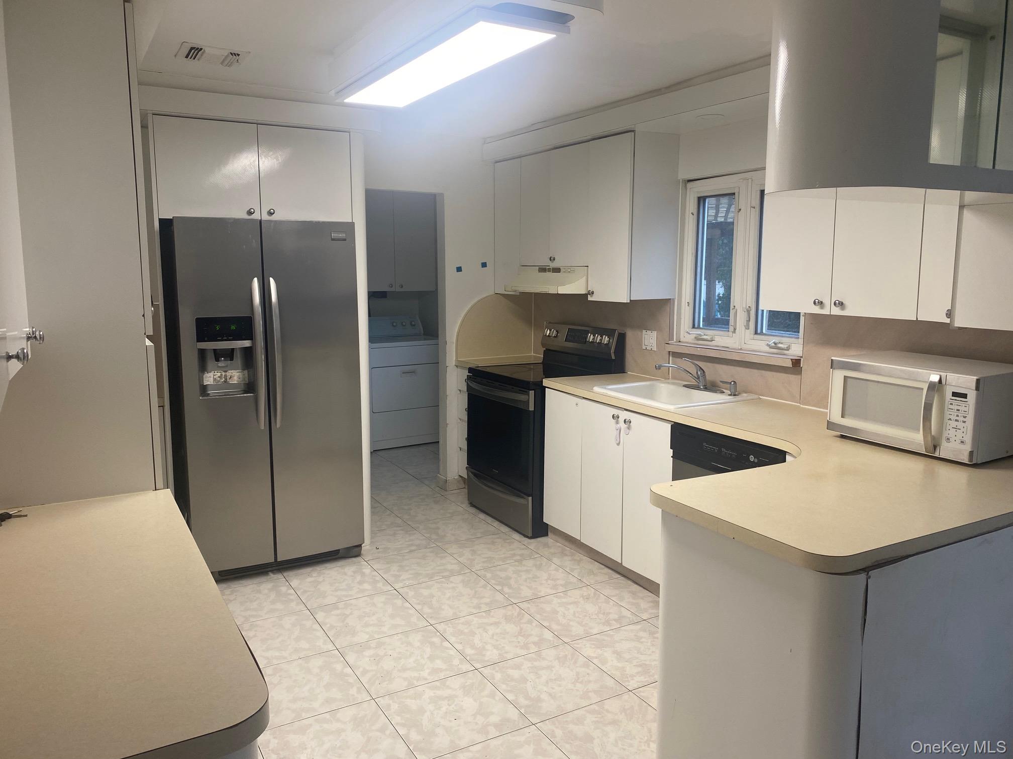 723 Hungry Harbor Road Valley Stream, NY 11581 - Photo 4 of 19 a kitchen with a sink a refrigerator and cabinets