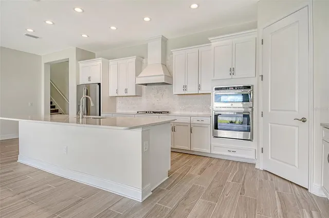 a kitchen with cabinets wooden floor and stainless steel appliances