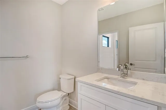 a bathroom with a granite countertop sink a toilet and a mirror