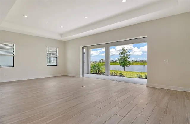 a view of an empty room with a window and wooden floor