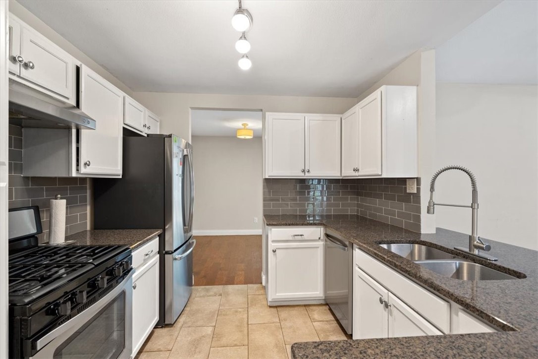 a kitchen with granite countertop a sink stainless steel appliances and cabinets