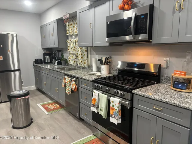 a kitchen with stainless steel appliances granite countertop a stove a sink and a microwave