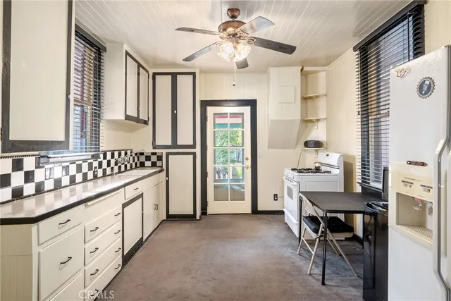 a kitchen that has a lot of cabinets in it with granite countertop a stove a sink a dining table and chairs