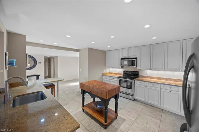 a kitchen with stainless steel appliances granite countertop a stove top oven a sink dishwasher a dining table and chairs with wooden floor