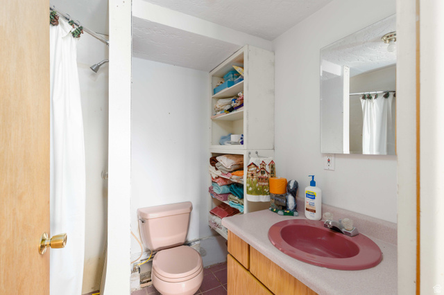 23 Scare Canyon, Unit 23 Logan, UT 84321 - Photo 16 of 33 Bathroom featuring a pink commode, a built-in shower with a white curtain, a vanity with a pink countertop and integrated sink, a mirrored medicine cabinet, and open shelving