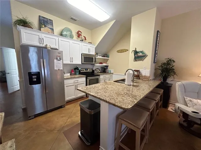 a kitchen with stainless steel appliances granite countertop a sink refrigerator and microwave