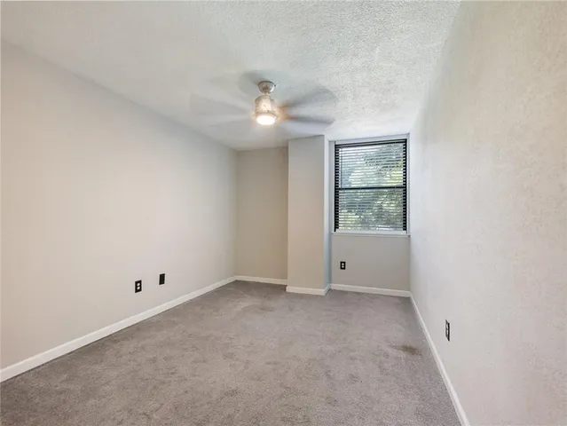 an empty room with a window and ceiling fan