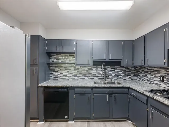 a kitchen with granite countertop a sink cabinets and stainless steel appliances