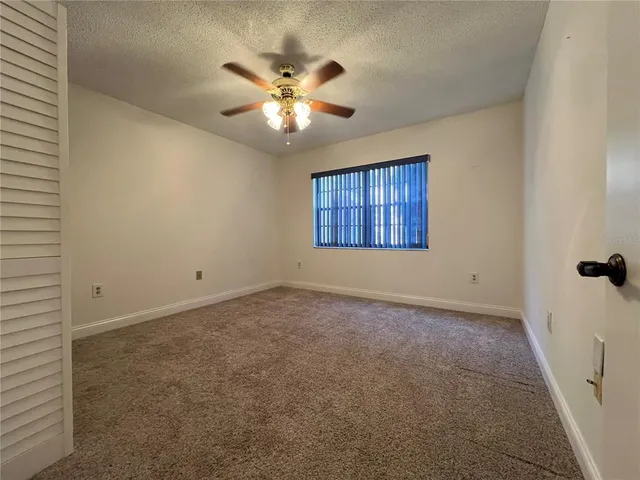 an empty room with a chandelier fan and windows