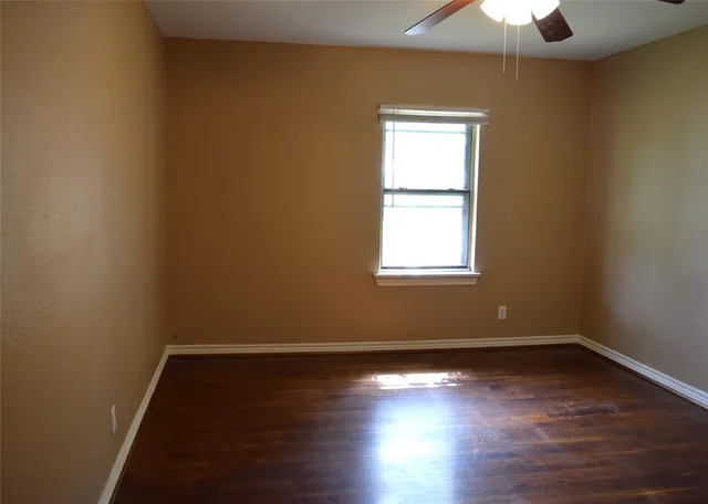 an empty room with wooden floor closet and windows