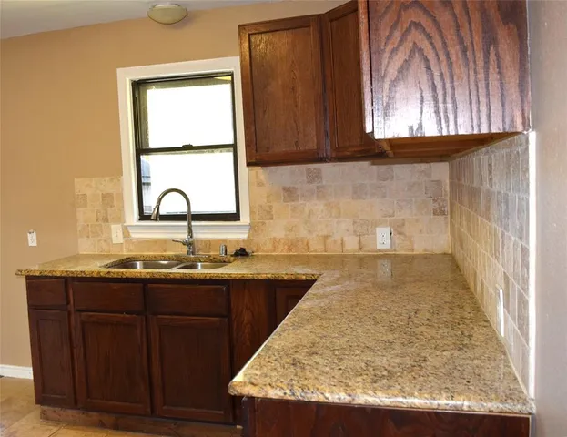 a kitchen with granite countertop a stove top oven microwave and cabinets
