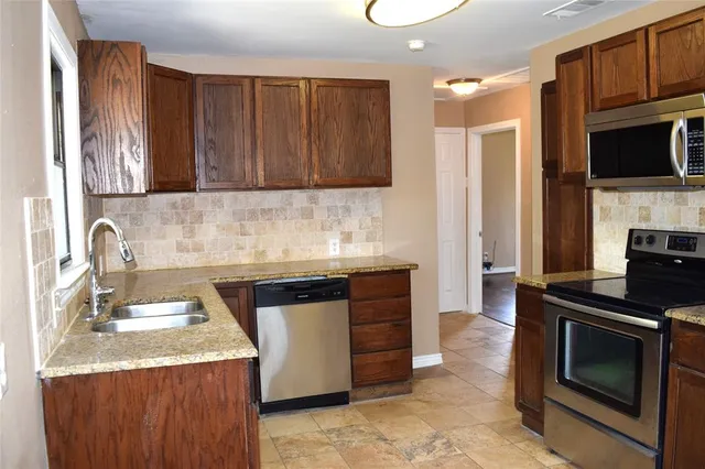 a kitchen with granite countertop a sink dishwasher stove and cabinets