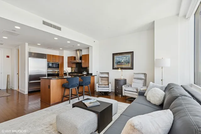 a living room with furniture kitchen view and a wooden floor