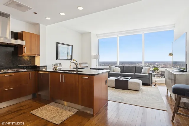 a living room with stainless steel appliances granite countertop a sink dishwasher stove and cabinets