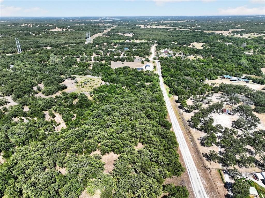 130 R&R Drive Springtown, TX 76082 - Photo 7 of 40 Expansive treed landscape with scattered cleared areas and a visible roadway