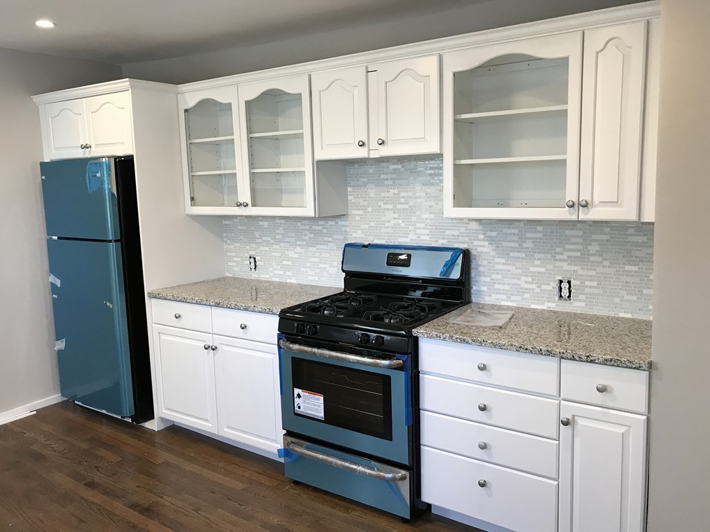 a kitchen with granite countertop white cabinets and appliances