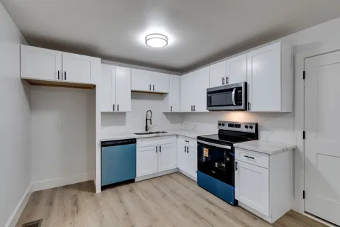 a kitchen with stainless steel appliances granite countertop white cabinets a sink a stove a microwave and a refrigerator