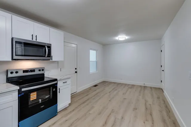 a view of kitchen with microwave stove refrigerator and cabinets