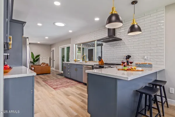 a kitchen with stainless steel appliances granite countertop a sink a stove and a wooden floors