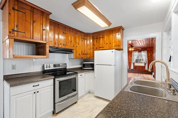 a kitchen with granite countertop a stove a sink and a refrigerator