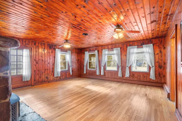 a view of an empty room with window and wooden floor