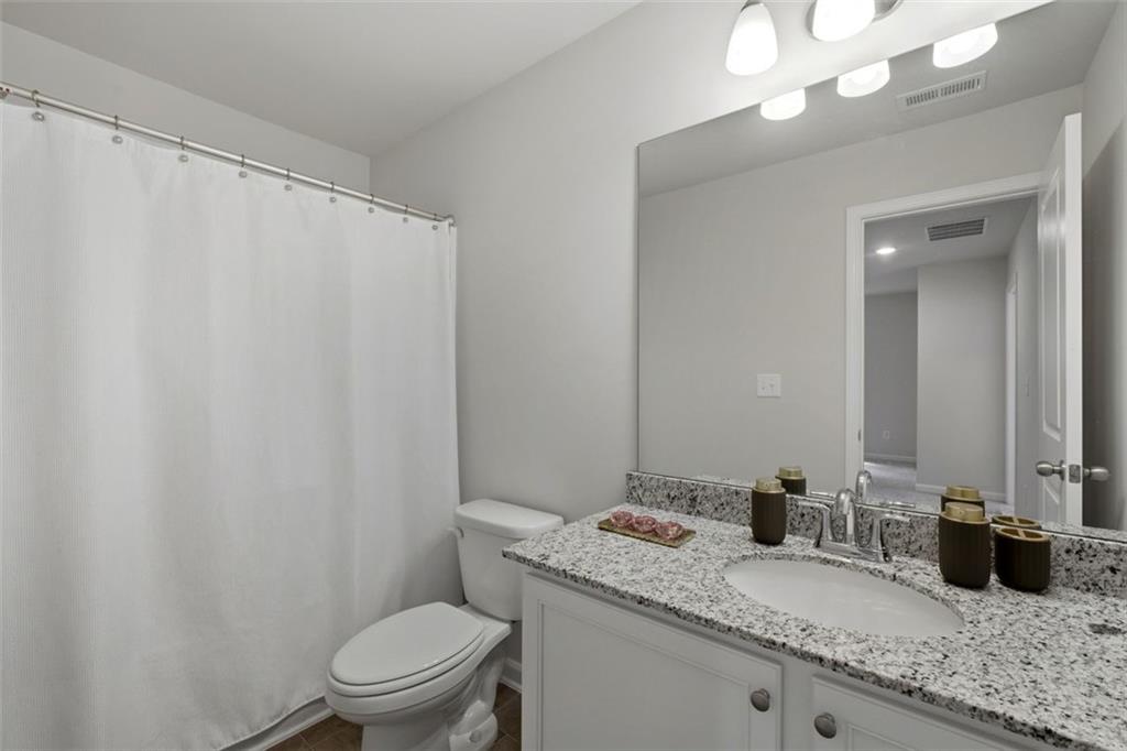 1242 Riverstone Road Jonesboro, GA 30238 - Photo 30 of 38 a bathroom with a granite countertop sink vanity mirror and toilet