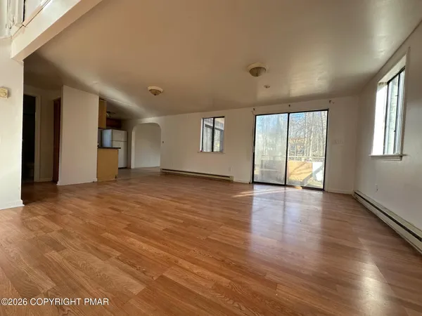 an empty room with wooden floor and windows