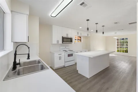 a kitchen that has a lot of cabinets in it and wooden floors