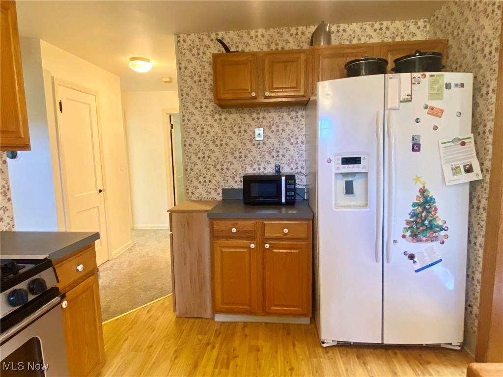 1568 Sunview Road Cleveland, OH 44124 - Photo 14 of 50 Kitchen with white refrigerator with ice dispenser, dark countertops, light wood-style flooring, and brown cabinets