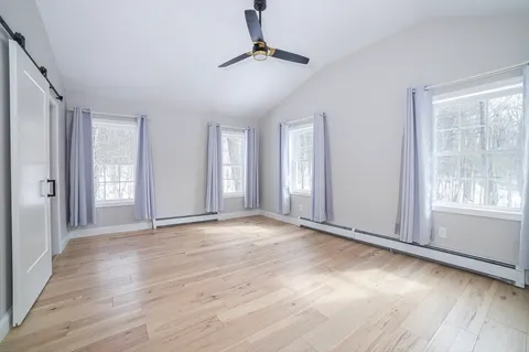a view of an empty room with window and wooden floor