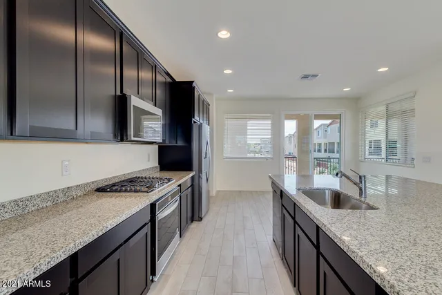 a kitchen with stainless steel appliances granite countertop a sink a stove and a wooden floors