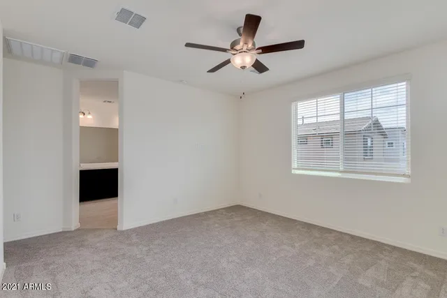 a view of a livingroom with a ceiling fan & windows