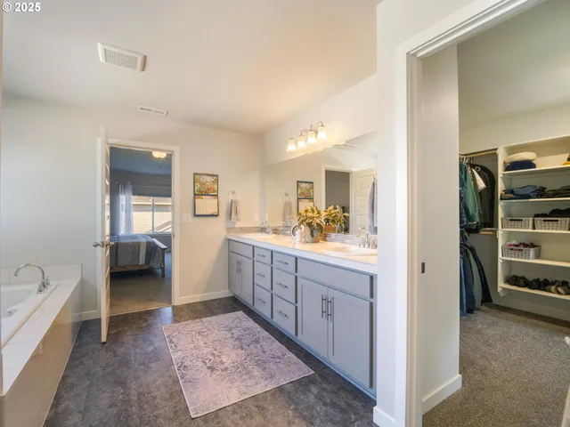 a en suite spacious bathroom with a double vanity sink a mirror and a bathtub