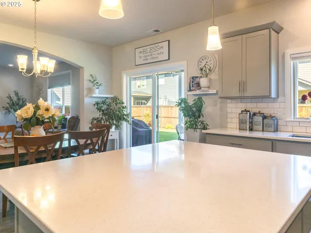 a large white kitchen with kitchen island granite countertop a sink a counter top space and living room view