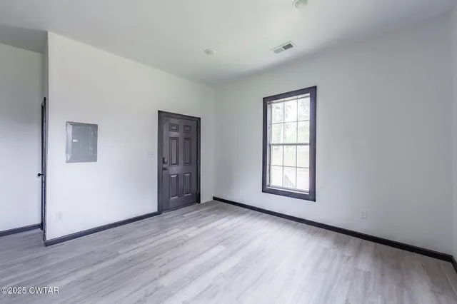 a view of an empty room with wooden floor and window