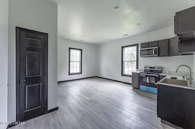 a living room with stainless steel appliances granite countertop furniture wooden floor and a window