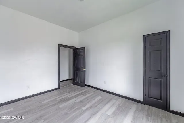 a view of an empty room with wooden floor and closet