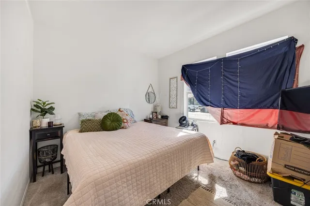a bedroom with a bed a dresser and a potted plant