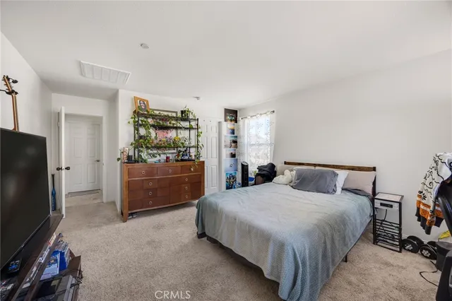 a bedroom with a bed and a flat tv screen on dresser