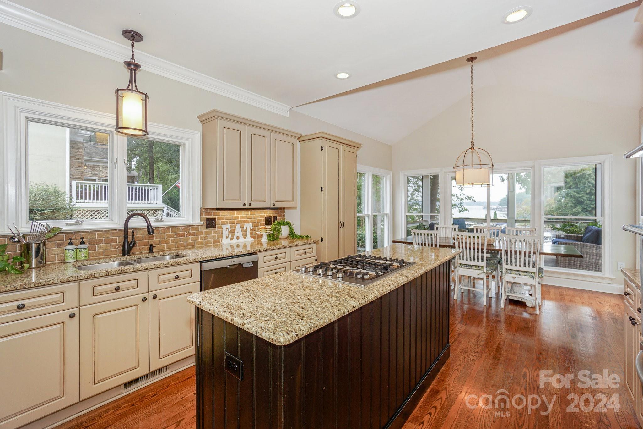 21910 Satilla Drive Cornelius, NC 28031 - Photo 17 of 47 a kitchen with a stove a sink dishwasher white cabinets and couches with wooden floor