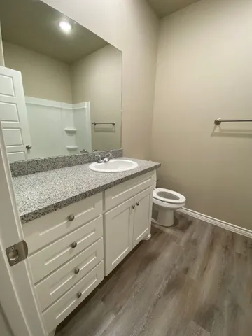a bathroom with a granite countertop toilet and sink