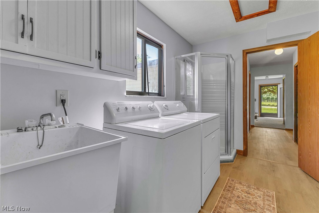 6635 Taylor Road Painesville, OH 44077 - Photo 14 of 41 Utility room featuring a built-in laundry sink, white cabinetry with dark hardware, and a clear glass shower enclosure