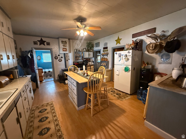 379 Main Street Georgetown, ID 83239 - Photo 4 of 23 Kitchen featuring a central island with integrated seating, wood-finish flooring, white cabinetry, a built-in sink, and a ceiling fan