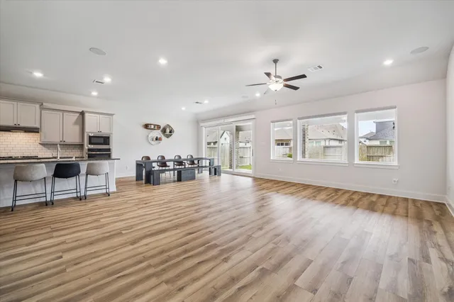 a view of an empty room with window and wooden floor