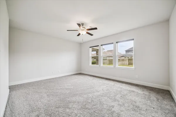 an empty room with windows and ceiling fan