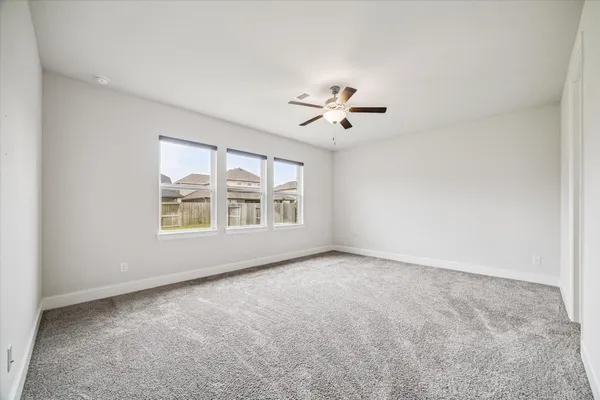 an empty room with windows and chandelier fan