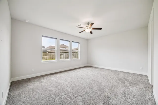 an empty room with windows and chandelier fan